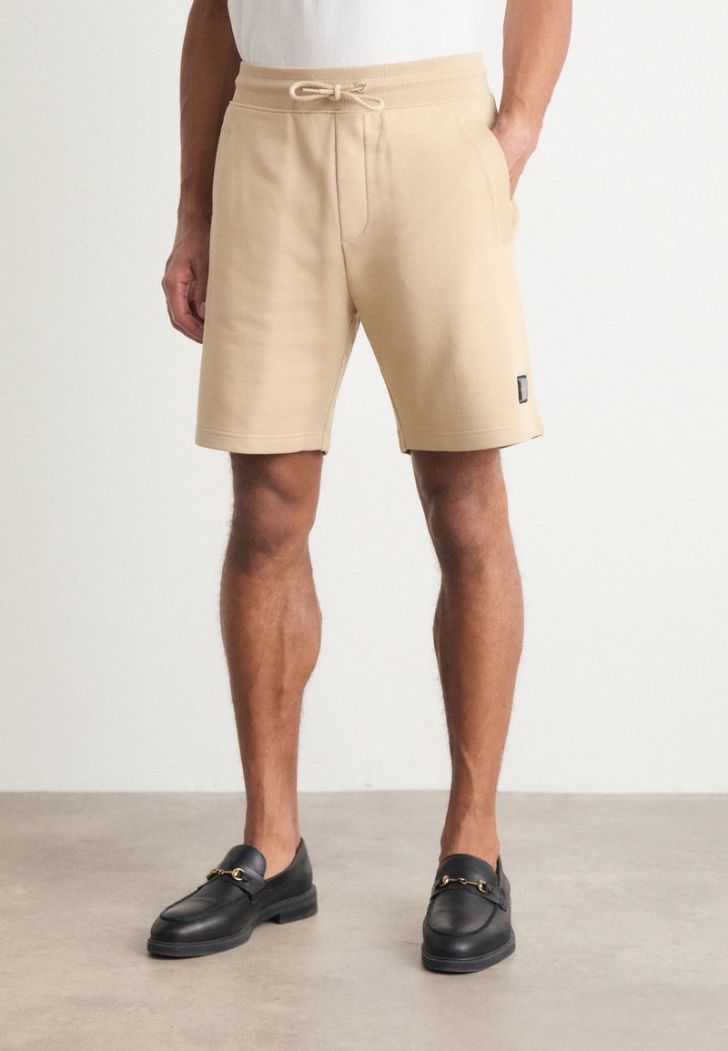 Beige shorts i bomullsblandning med elastisk midja och dragsko. Har sidofickor och en liten logotyp vid nederkanten.