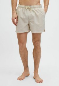 Beige vævede badshorts med elastisk talje, snor, sidelommer og et tekstureret mønster. Over knæ længde, afslappet pasform.