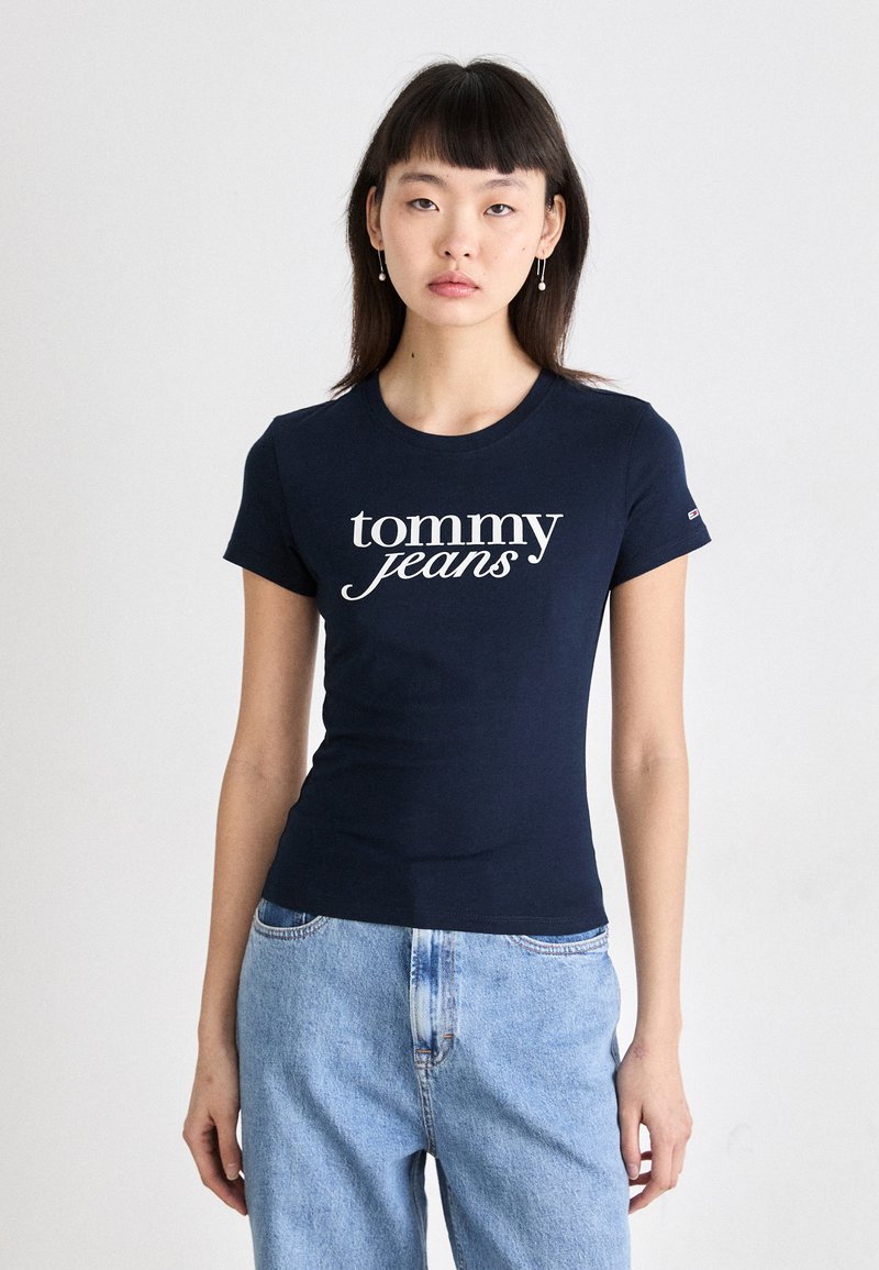 Námořnická modrá přiléhavá tričko vyrobené z bavlny, s bílým logem "tommy jeans" na přední straně. Krátké rukávy a kulatý výstřih.