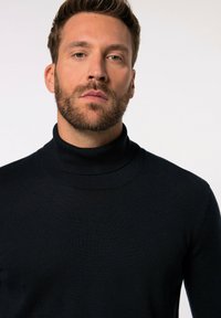 Marineblauer Rollkragenpullover, gerippter Kragen und Bündchen, taillierte Form, aus einem weichen, strukturierten Stoff.