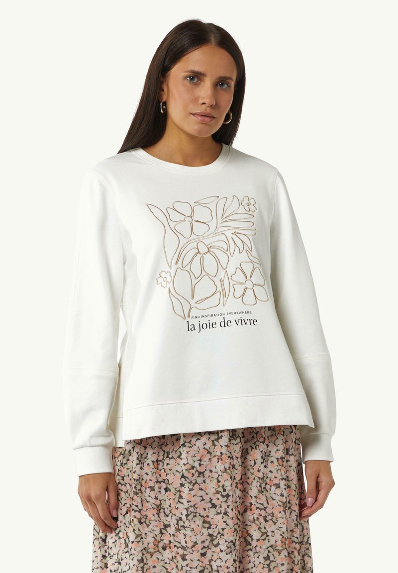 Witte sweatshirt met een bloemige lijntekening in bruin, voorzien van een ronde hals en lange mouwen. Gecombineerd met een rok met bloemenpatroon.