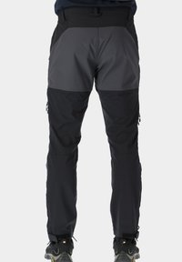 Mustat ulkoiluhousut, joissa on harmaa yläosa, vetoketjulliset sivutaskut, säädettävä vyötärö ja kapeneva lahjetyyli.