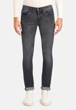 Jean en denim gris avec une coupe slim, légère décoloration, design à cinq poches et revers aux chevilles. Associés à des baskets blanches.