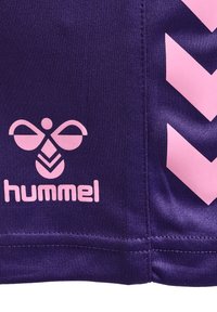 Tejido deportivo morado con un logo rosa que presenta un diseño de mariposa y acentos en chevron rosa a lo largo del borde.