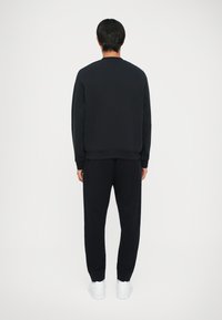 Marineblauwe sweatshirt en joggingset, gemaakt van zachte stof. De sweatshirt heeft een ronde halslijn en een ontspannen pasvorm, met bijpassende tapers joggers.