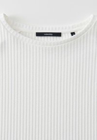 White, ribbed knit top featuring a round neckline and a tag displaying the brand "someday." Texture is soft, with even vertical lines.