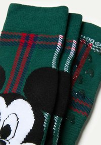 Grønne sokker med et ternet mønster i rød og marineblå, med sorte Mickey Mouse-designs og teksturerede detaljer over overfladen.