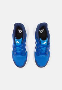 Baskets de sport bleues avec une tige en maille, des rayures blanches et un col rembourré. Présentent des accents gris, des lacets plats et une semelle texturée.