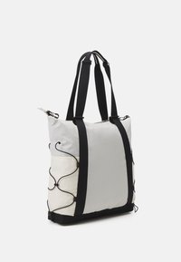 Torba typu tote w jasnoszarym i kremowym kolorze z czarnymi akcentami. Posiada fakturowaną powierzchnię, regulowane paski oraz dekoracyjne metalowe detale.