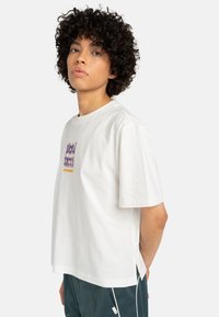 White cotton t-shirt with short sleeves, featuring a colorful graphic design on the front and side slits at the hem for comfort.