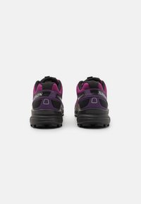 Sapatos de corrida de montanha com um design preto e roxo, parte superior em malha, colarinho acolchoado e sola multidirecional para tração.
