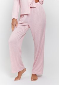 Conjunto de pijama de rayas en rosa claro con pantalones largos y chaqueta con botones. Tejido suave, corte relajado y puños enrollados en los tobillos.