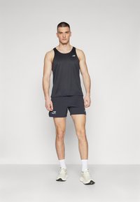 Black athletic tank top and shorts made of lightweight fabric, featuring a logo, fitted design, and white accents. Worn with sneakers.