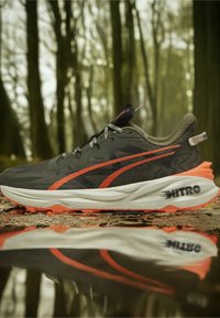 Szare i czarne buty do biegania z teksturowaną cholewką, jasnopomarańczowymi akcentami i masywną białą podeszwą z logo "NITRO".