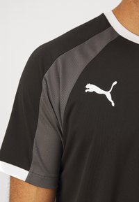 Black athletic shirt with gray textured shoulder panels, white crew neck, and a white Puma logo on the chest.