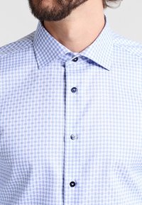 Modrá a bílá kostkovaná košile z bavlny s rozšířeným límcem a černými knoflíky. Látka má hladkou strukturu s mřížkovým vzorem.