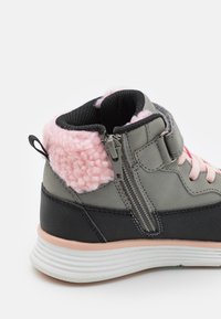Baskets montantes grises et noires avec un col en polaire rose, des détails en zip, des panneaux texturés et une semelle en caoutchouc blanche striée.