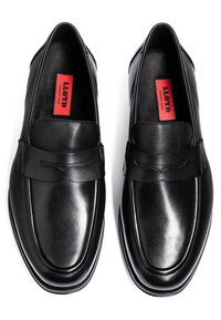 Schwarze Lederloafers mit glatter Oberfläche, quadratischer Spitze, dekorativer Naht und einem breiten Lederriemen über dem Spann mit dezenter Detailgestaltung.