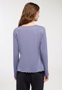 Maglietta a maniche lunghe di un leggero colore viola, con una vestibilità morbida, scollatura rotonda e orlo ondulato. Texture morbida con una leggera trasparenza.