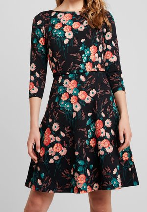 Robe noire avec un motif floral rose et turquoise, manches trois-quarts, taille cintrée avec une ceinture en tissu, et jupe évasée.