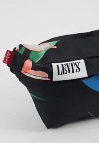 Pochette en tissu noir Levi's avec des imprimés floraux, avec une étiquette blanche Levi's et une petite étiquette rouge Levi's cousue sur le côté.