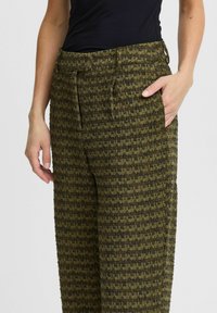 Pantalons verts et noirs à motif avec une finition texturée, dotés de poches latérales et d'une coupe décontractée. Conçus pour le confort et la polyvalence.