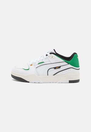 White sneaker with green and black accents. Leather upper with perforations, rubber sole, lace-up design, and side branding details.