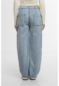 Gai zilo denima kravas bikses ar platām kājām, divām lielām sānām kabatām, sānu kabatu detaļām un etiķeti jostas vietā.