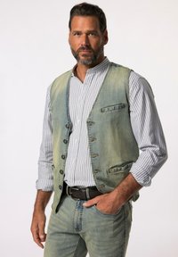 Jeansweste in einem Farbverlauf von Blau zu Grün, mit sechs Knöpfen und zwei vorderen Taschen, über einem gestreiften Hemd mit Knöpfen und passenden Jeans.