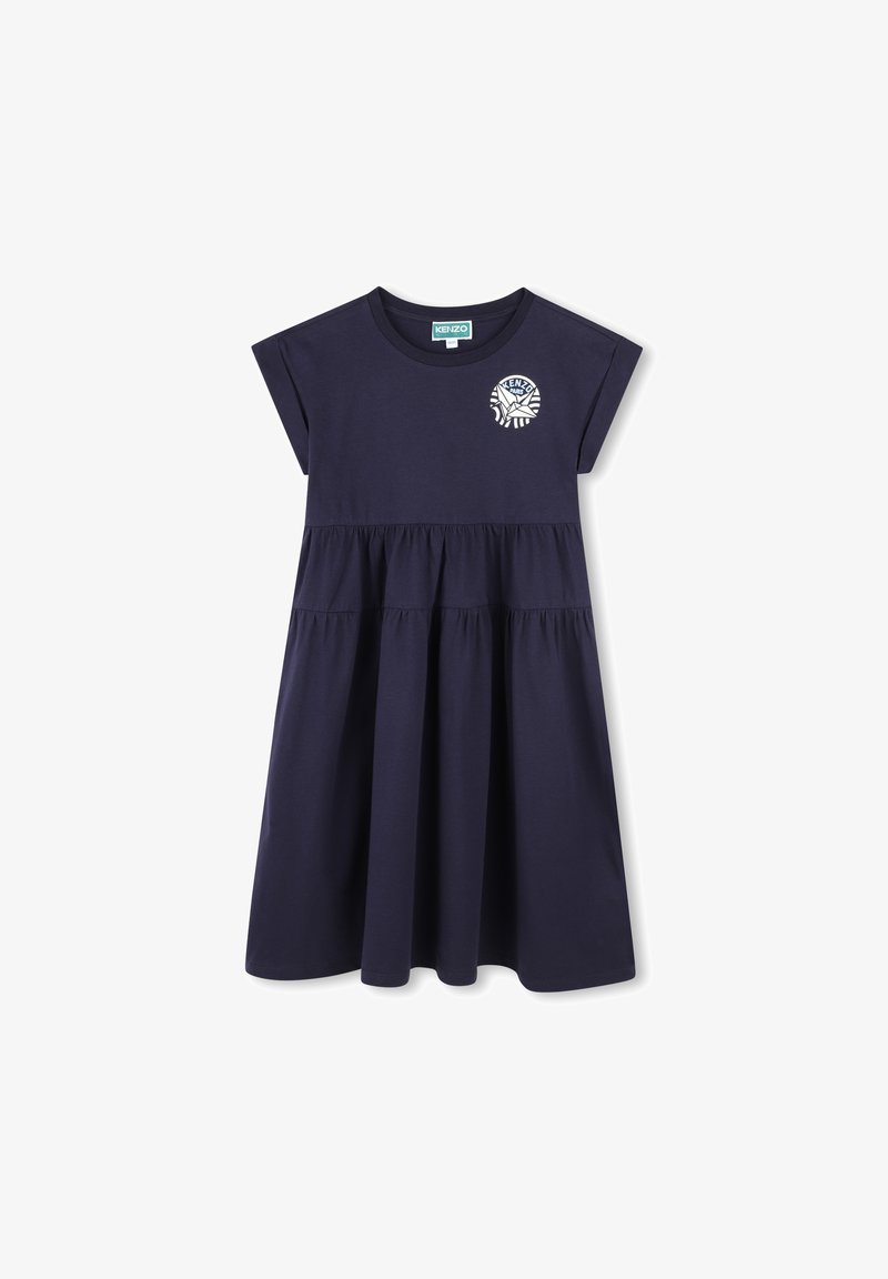 Marineblauwe katoenen jurk met korte kapmouwen, gelaagd ontwerp en een witte grafische logo op de borst. Glad textuur, tot de knie.