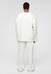 Witte oversized sweatshirt en bijpassende sweatpants van zachte stof, met een ontspannen pasvorm en minimalistisch ontwerp.