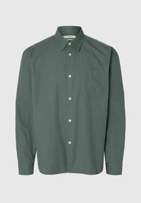 Chemise à manches longues, verte foncée, boutonnée, avec col pointu et une poche poitrine, présentée sur fond blanc.
