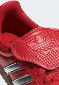 Röda lädersneakers med en vadderad tunga, prägling av logotypen och silverstripes. Har texturerade detaljer och en gummisula.