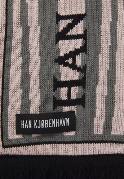 Adītas šalles ar maiņojošām pelēkām un gaiši rozā svītrām, ar melnu tekstu un pušķu detaļu. Uz birkas uzrakstīts "HAN KJØBENHAVN."