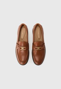 Brown leather loafers with a rounded toe and gold-tone hardware accent. Features stitched detailing and a textured insole. Flat rubber sole.