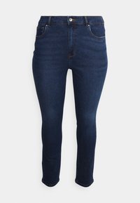 Vaqueros skinny azul oscuro con cinco bolsillos, presillas para el cinturón y cremallera. Hechos de denim con una textura suave y sutiles detalles de costura.
