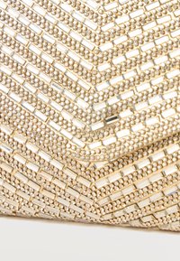 Primer plano de un clutch tono dorado con patrón de chevrón hecho de pequeños brillantes redondos y rectangulares transparentes.