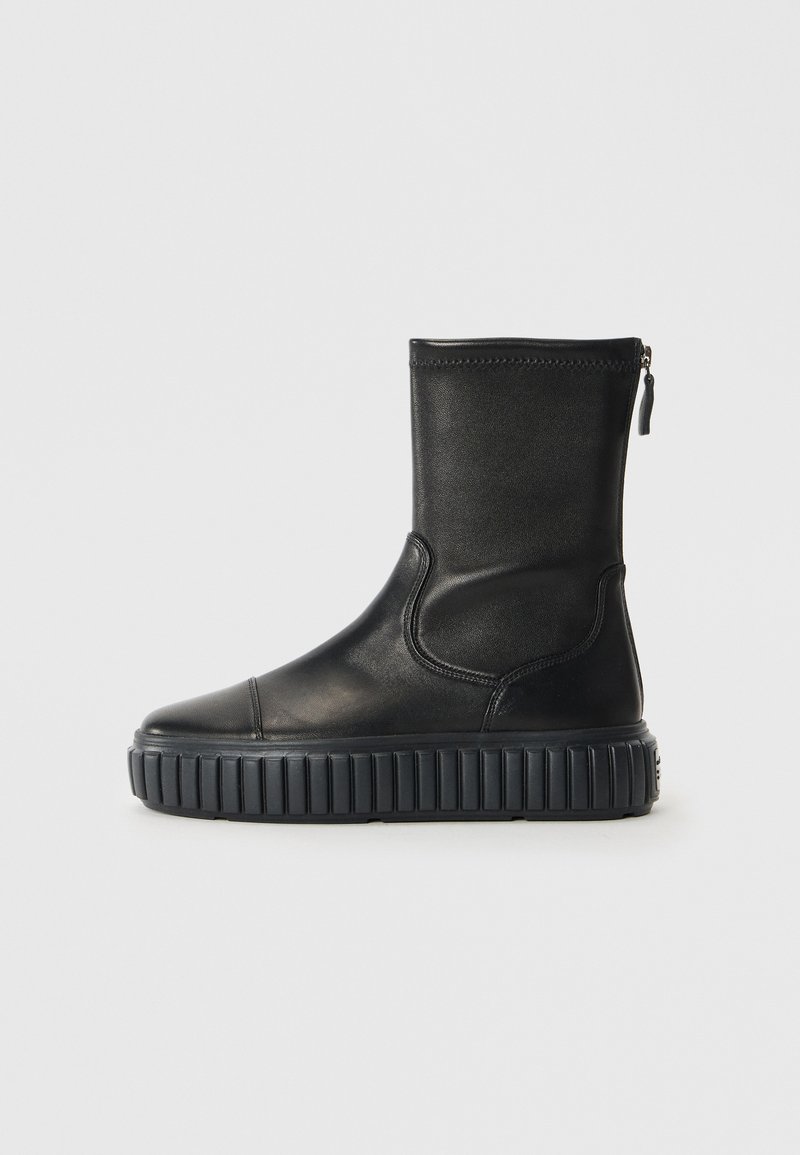 Botte chelsea en cuir noir avec un bout rond, une semelle crantée et une fermeture éclair sur le côté. Sa texture lisse et son design minimaliste mettent en valeur son esthétique moderne.