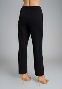 Pantaloni neri a gamba dritta, tessuto liscio, design sartoriale, vita media, abbinati a décolleté nude, senza dettagli visibili sul retro.