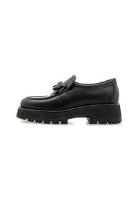 Zapato de cuero negro con punta redondeada, una correa decorativa y una suela de goma gruesa y texturizada. Diseño minimalista con sutiles detalles de costura.