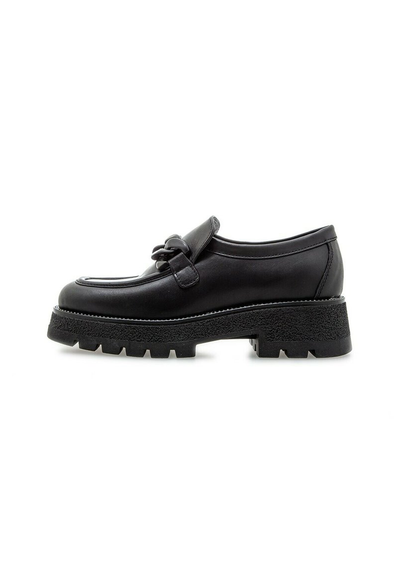 Zapato de cuero negro con punta redondeada, una correa decorativa y una suela de goma gruesa y texturizada. Diseño minimalista con sutiles detalles de costura.