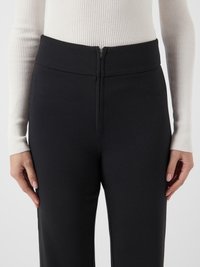 Czarne spodnie z wysokim stanem, zapinane na zamek z przodu, o gładkiej fakturze i dopasowanym kroju. Zaprojektowane z pionowymi szwami dla uzyskania strukturalnego wyglądu.