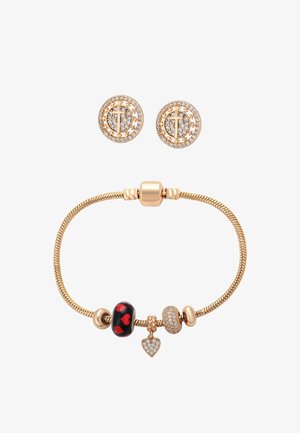 Bransoletka z zawieszkami w złotym odcieniu z koralikami w kształcie serca i ozdobionymi kryształkami, w komplecie z okrągłymi złotymi kolczykami na sztyfcie z kryształowymi akcentami.