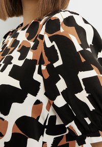 T-shirt met korte mouwen met een zwart, wit en bruin abstract patroon; gladde stof; geplooide schouderdetails; ontspannen pasvorm.