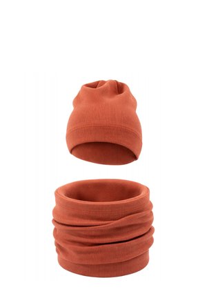 Prążkowana, dziergana czapka w kolorze rdzy oraz pasujący komin, pokazane osobno na białym tle.