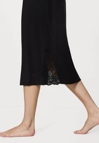 Czarna sukienka z koronkowym akcentem na bocznym wykończeniu, wykonana z miękkiego materiału, o prostym kroju i długości do połowy uda.