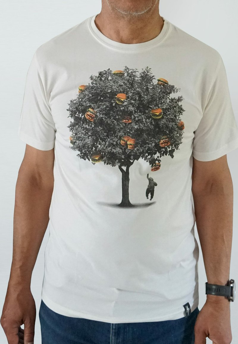 White t-shirt featuring a graphic of a tree with burgers as foliage, and a small figure reaching for one. Soft fabric, casual fit.
