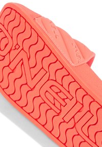 Lys korallfärgad sandaler i slidmodell med texturerad gummisula, som har ett vågmönster och Präglad logotypdetalj. Slank och lätt design.