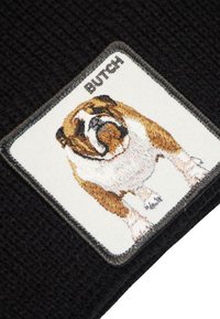 Tessuto nero a maglia con un patch ricamato rettangolare di un bulldog con l'etichetta "BUTCH," con dettagli di pelliccia color nocciola e bianco.