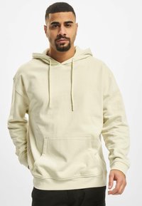 Kridhvid oversized hoodie med en lomme foran, snoretræk i huen og ribbede manchetter. Fremstillet af blødt bomuldsmateriale.